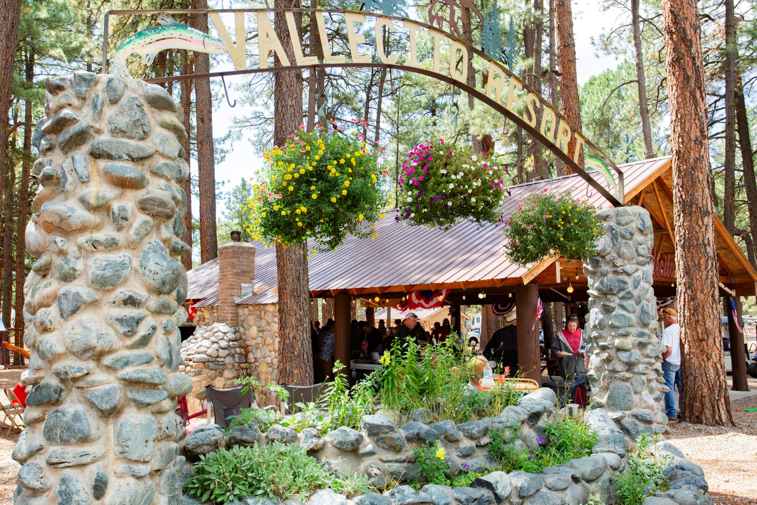A stone archway with flowers and a building in the background.